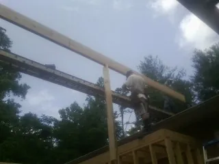 Carpenter setting a ridge beam over a new addition frame — Ice Dam Removal by Roofing Brothers in Moriches