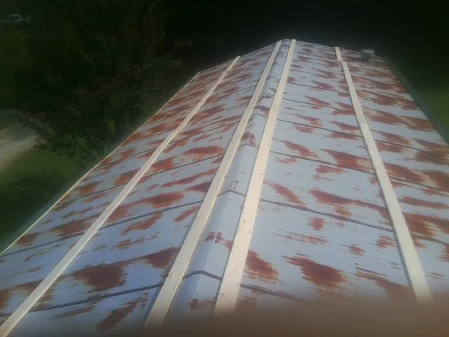 Rusted metal roof panels with new wood purlins before replacement — Storm Damage Roof Repair in Moriches by Roofing Brothers