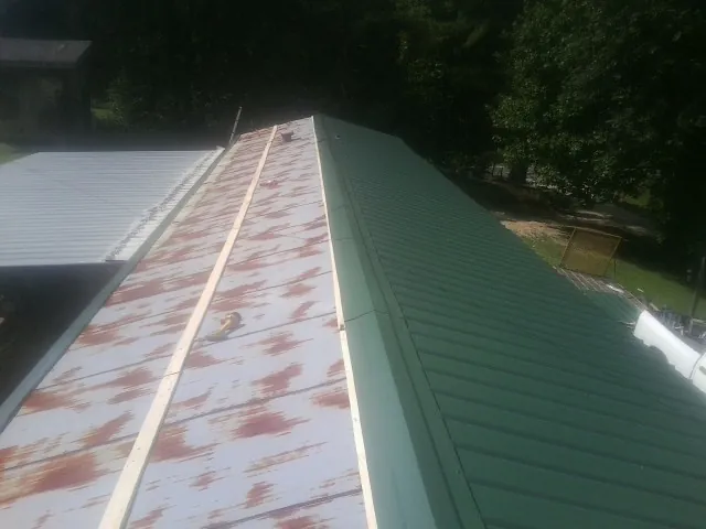 Old rusted panels beside newly installed green metal roofing — Wind Damage Roof Repair by Roofing Brothers in Moriches