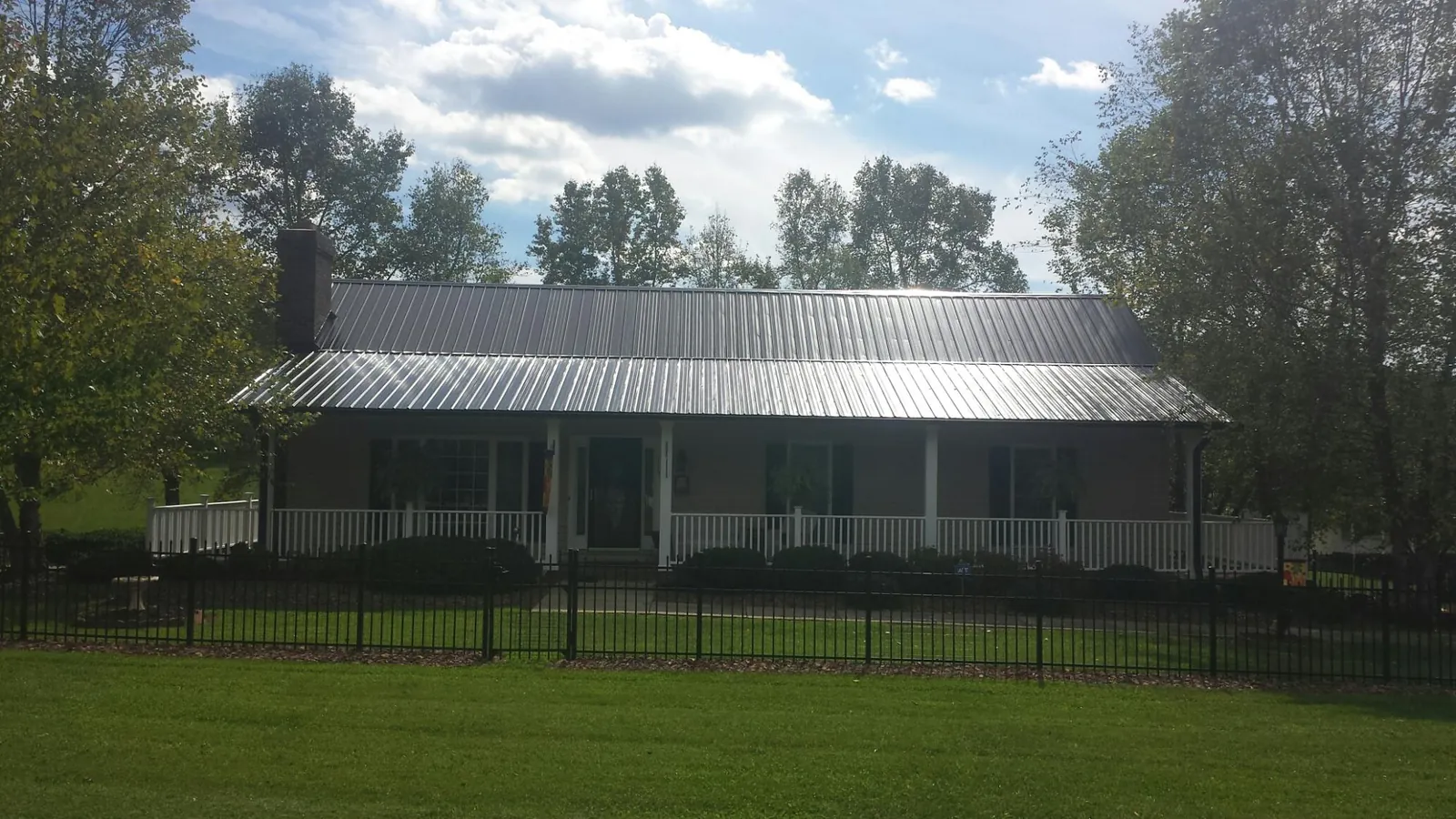 Gray metal roof on a brick ranch with a full width front porch — Gutter Guard Installation work by our crew in Moriches