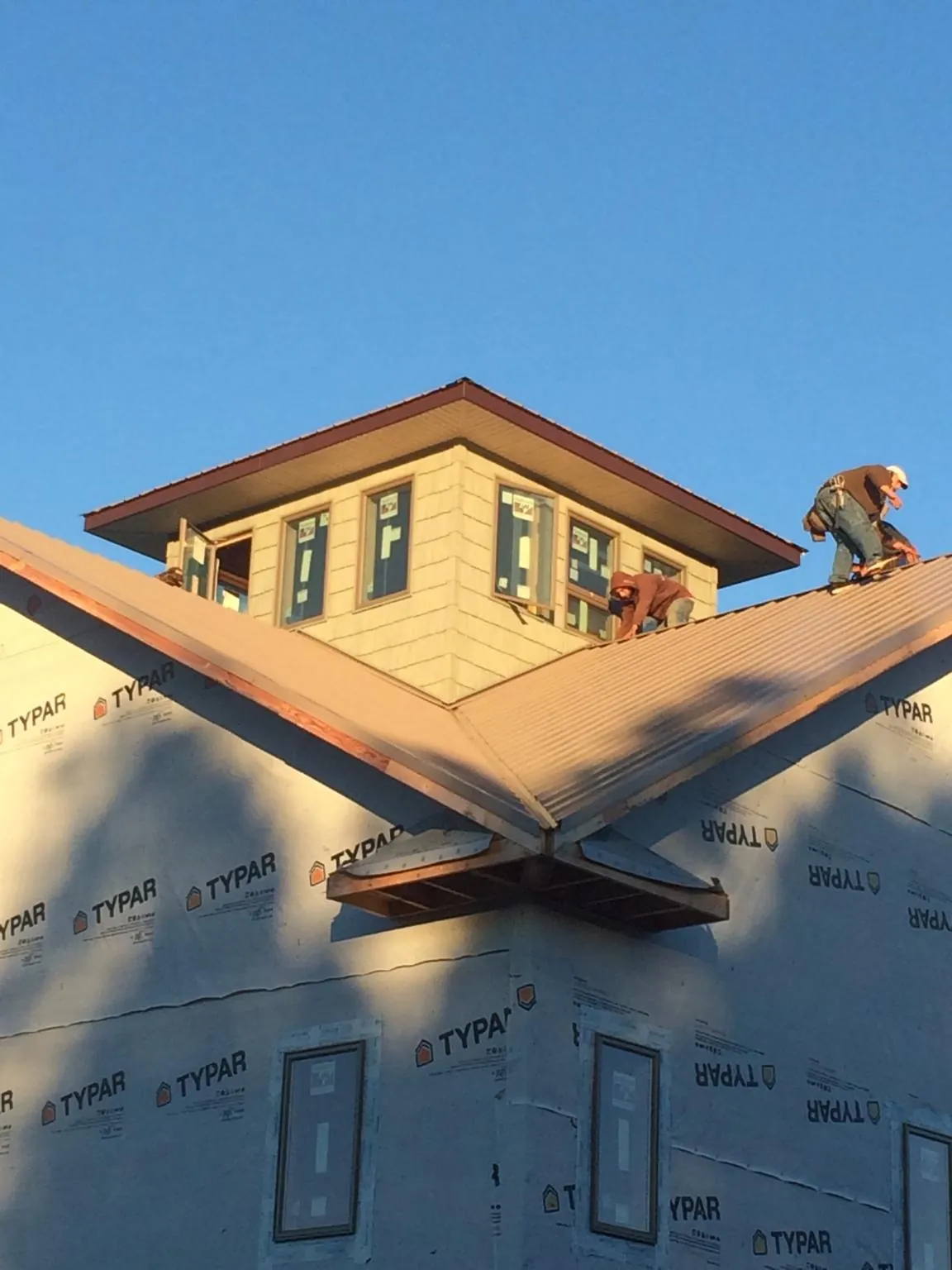 Roofers working around a rooftop cupola on a new metal roof at sunset — Roof Waterproofing in Moriches by Roofing Brothers
